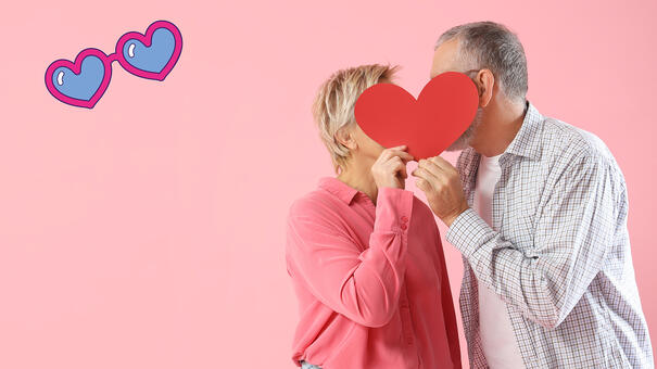 Couple se faisant un bisous caché derrière un cœur en carton