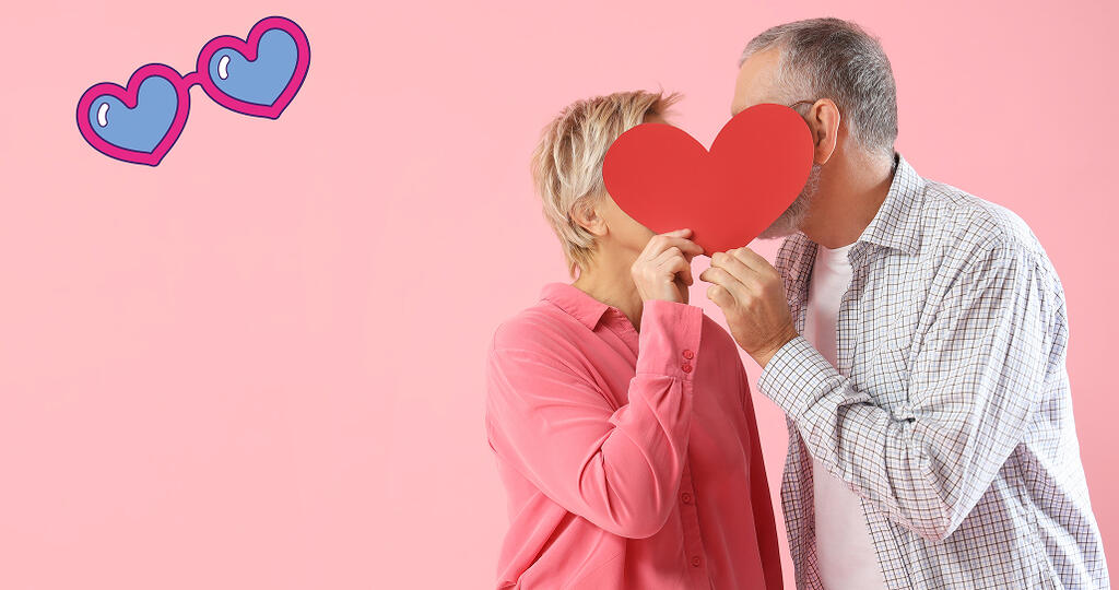 Couple se faisant un bisous caché derrière un cœur en carton