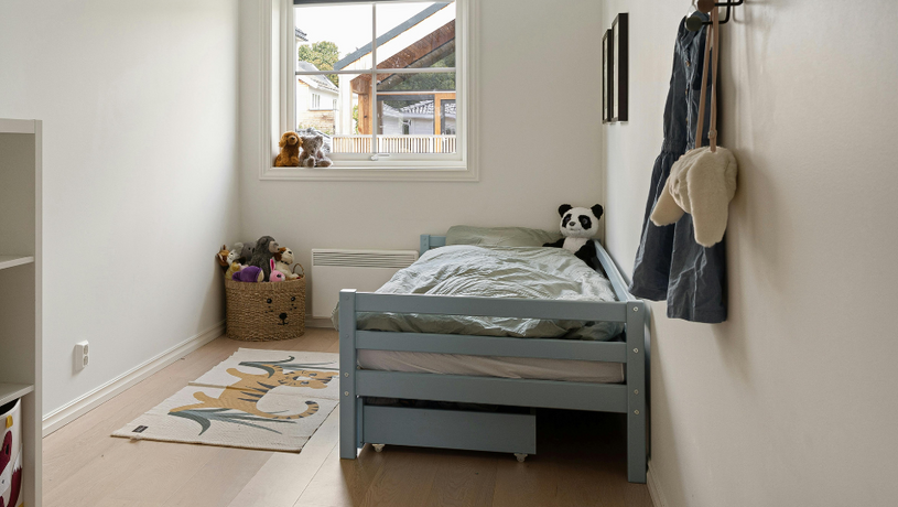 chambre d'enfant avec un lit simple, un tapis et une fenêtre 