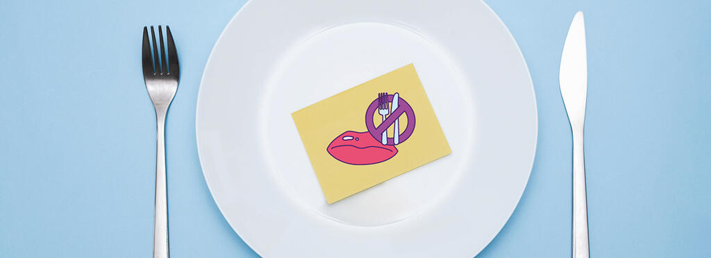 Une assiette et des couverts avec un dessin dans l'assiette d'une bouche fermée et des couverts barrés