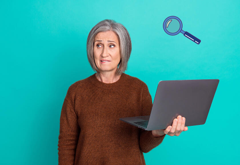 Personne âgé tenant un ordinateur avec un bras et se mordant la lèvre